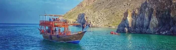 Musandam Dibba Trip from Dubai: Scenic coastline and crystal-clear waters during a boat tour.