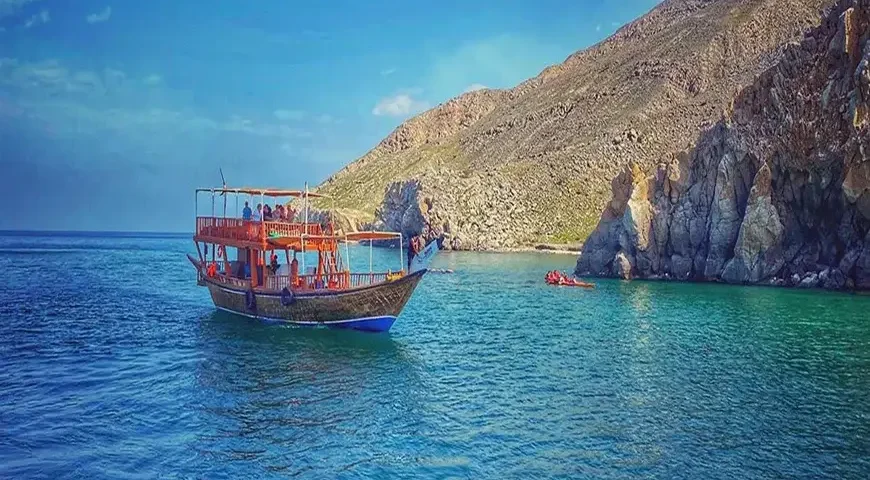 Musandam Dibba Trip from Dubai: Scenic coastline and crystal-clear waters during a boat tour.